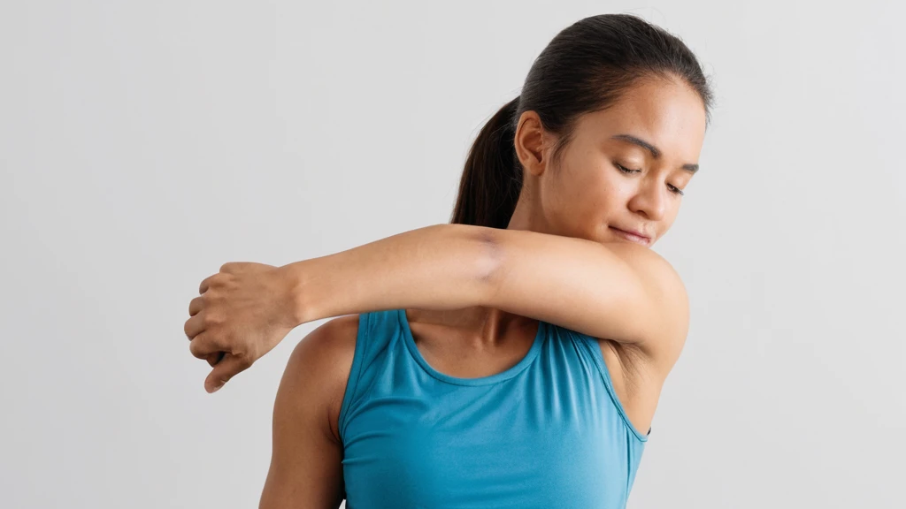 Mujer con ropa de deporte, realizando un estiramiento de hombros cruzando el brazo hacia el pecho